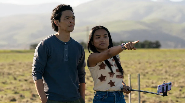 John Cho and Mia Isaac take a photo in a field in Don't Make Me Go