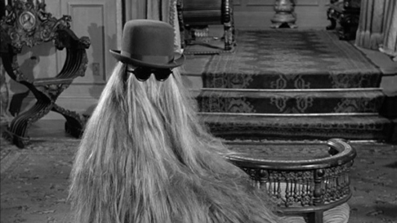 Cousin Itt wearing a bowling hat and sunglasses