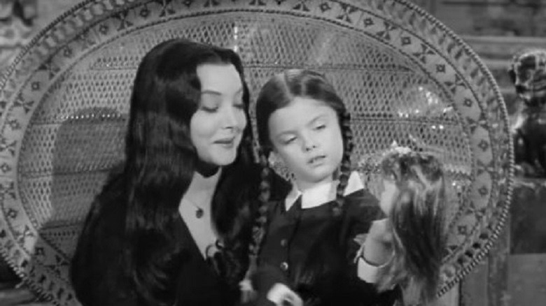 Wednesday Addams sitting on Morticia's lap