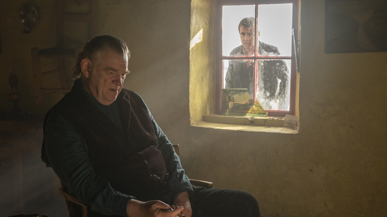 Colin Farrell looking through a window at a sad Brendan Gleeson