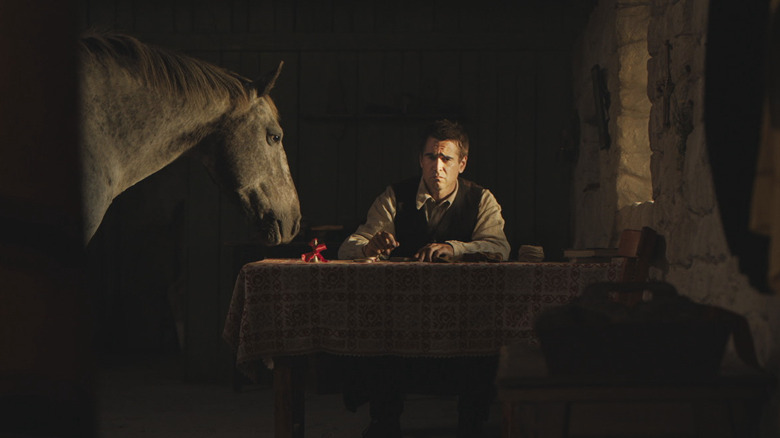 Colin Farrell looking sad in a room with a horse