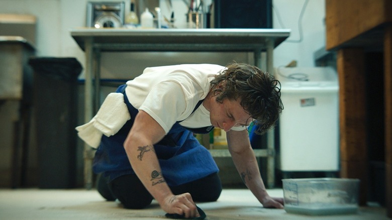 Carmy scrubbing floor in kitchen