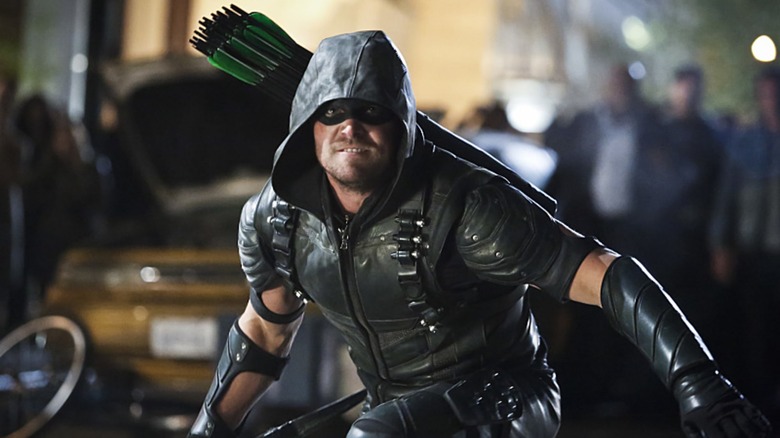 Oliver Queen stands on street with quiver of arrows