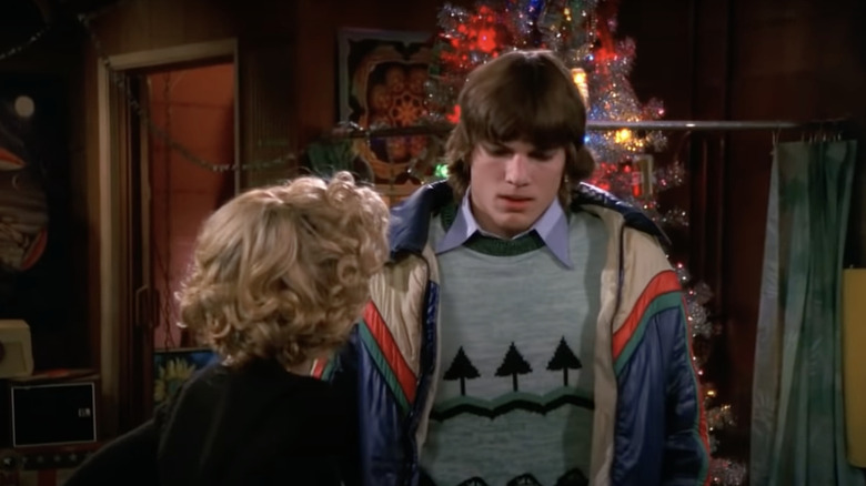 Ashton Kutcher standing in front of Christmas tree