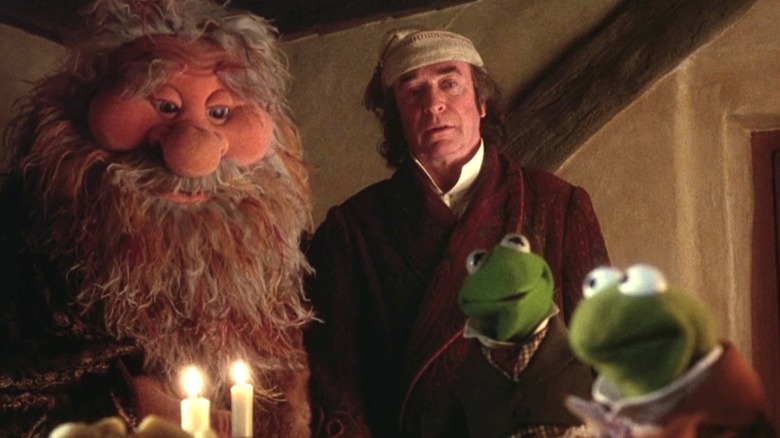 Michael Caine as Ebenezer Scrooge looking down at the Cratchits alongside the Ghost of Christmas Present in A Muppet Christmas Carol