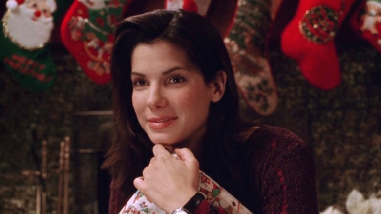 Sandra Bullock as Lucy Eleanor Moderatz holding a Christmas present and smiling in While You Were Sleeping (1995)