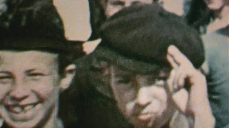 Two boys pose for a vintage photograph, one saluting