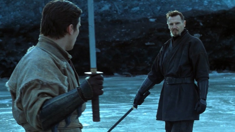 Christian Bale and Liam Neeson holding weapons