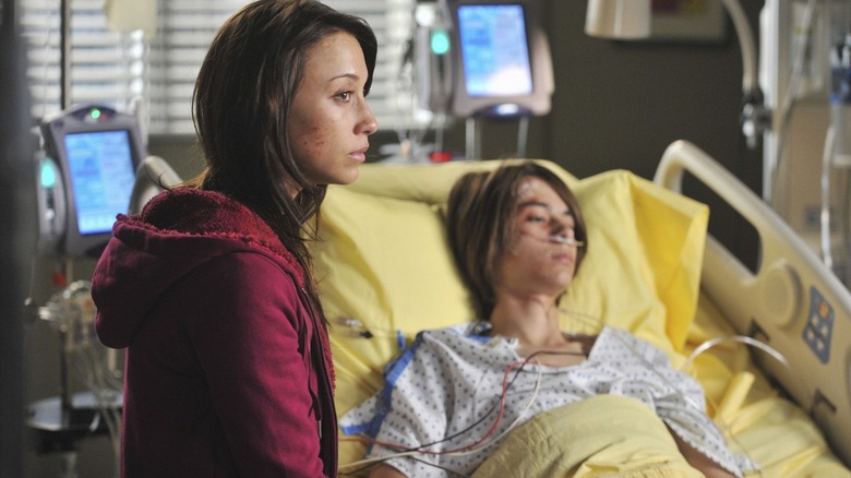 Woman waiting by patient in hospital bed