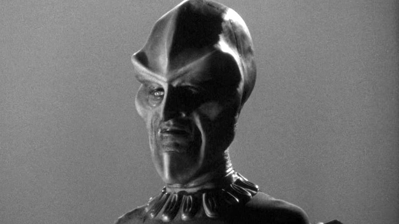 An Ebon alien holds a control device