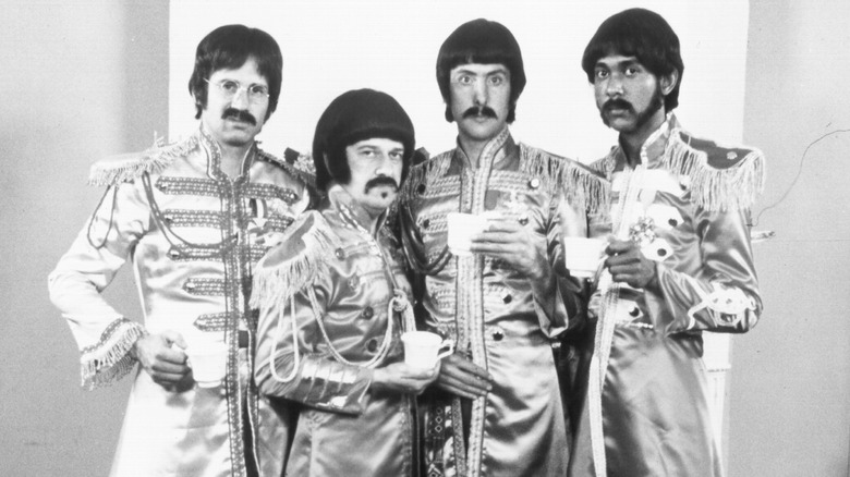 The Rutles hold cups of tea