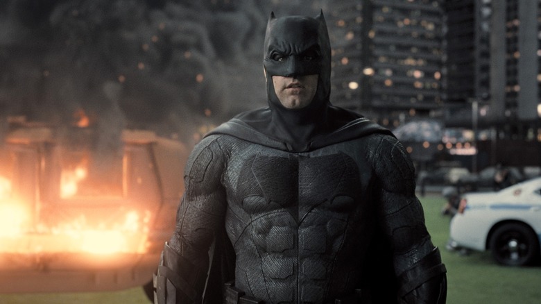 Batman stands near burning wreckage