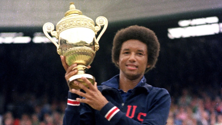 Arthur Ashe holds up trophy