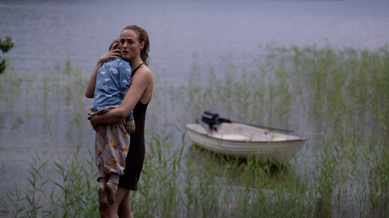 Mother carries child by water