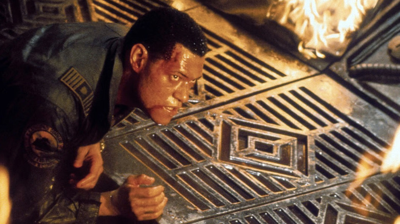 Laurence Fishburne leans on burning metal