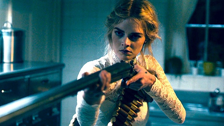 Samara Weaving holds up a gun 