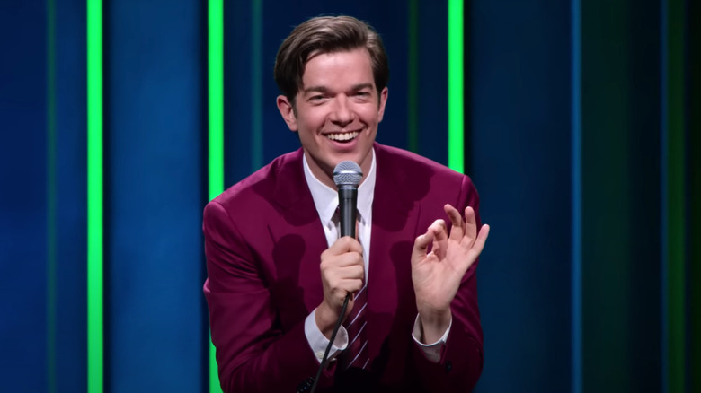 John Mulaney smiling while performing his stand-up special Baby J