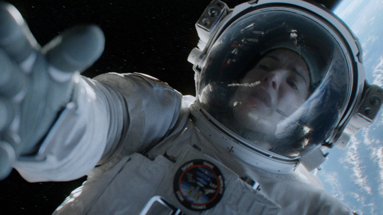 Sandra Bullock floating in space reaches out hand