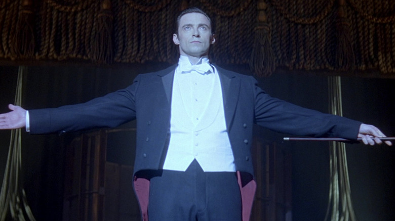 Hugh Jackman holds arms out wide on stage