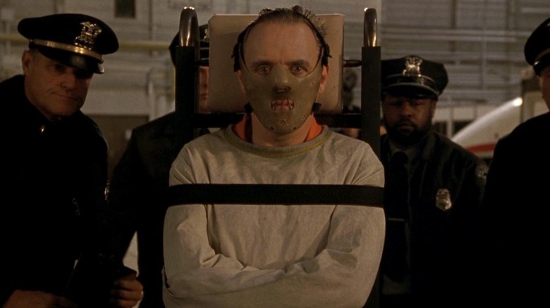 Dr. Hannibal Lecter strapped to dolly surrounded by cops