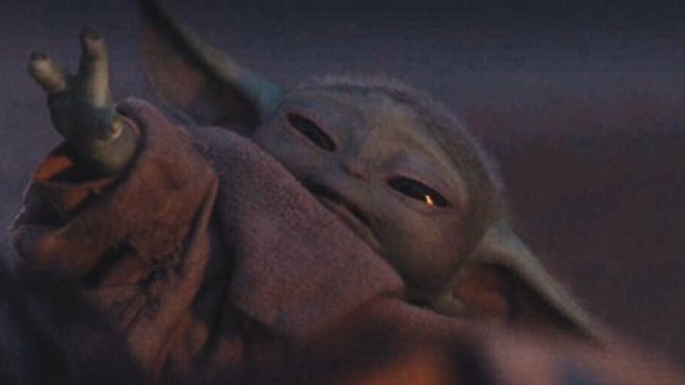 Baby Yoda reaching for The Mandalorian and melting all our cold dead hearts