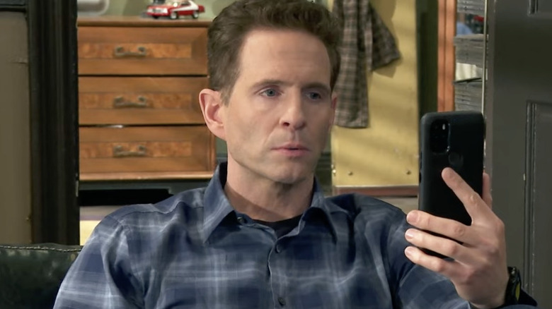 Dennis looking angrily at his cell phone