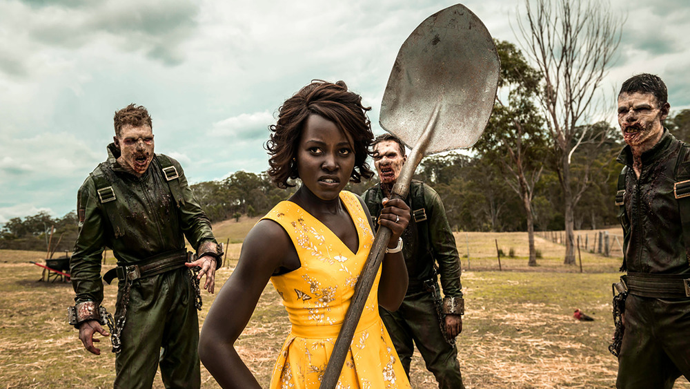 Miss Caroline holding a shovel with zombies behind her