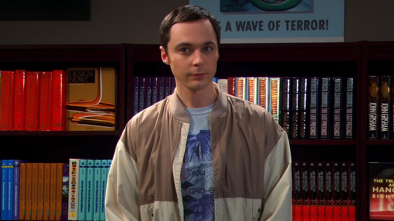 Sheldon standing in front of bookshelf