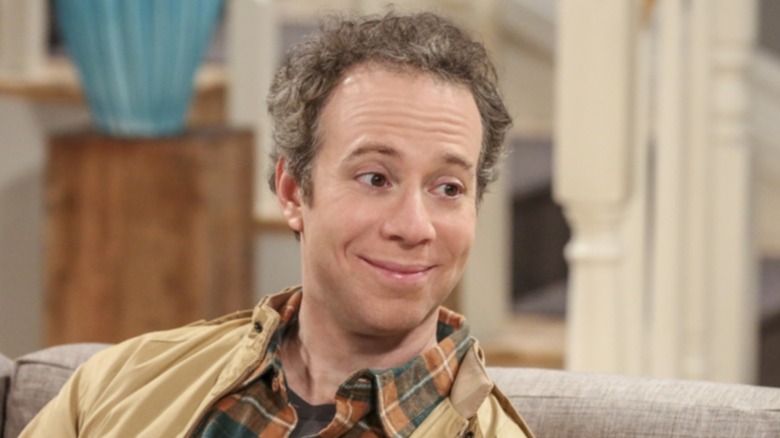 Stuart Bloom leans over and talks on The Big Bang Theory