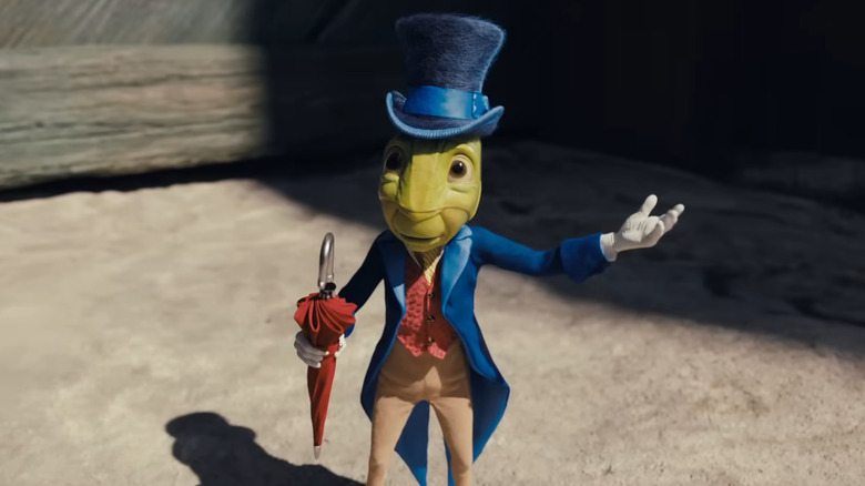 Jiminy Cricket standing politely with his arm extended