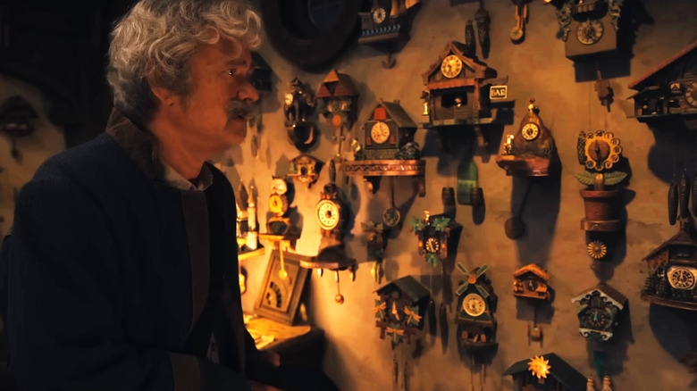 Geppetto standing in front of his wall full of clocks