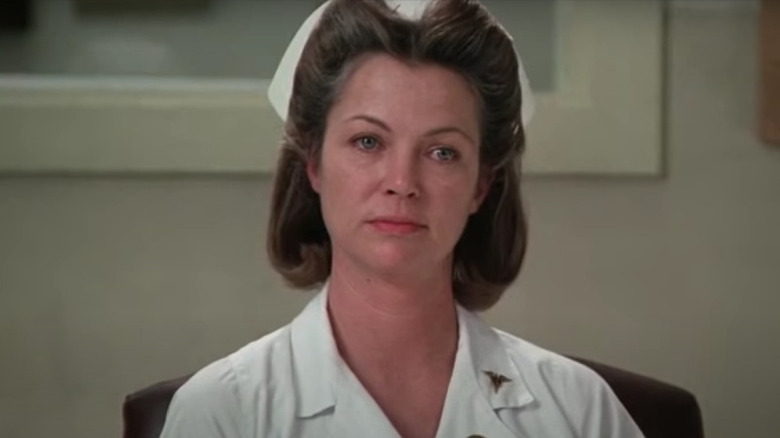 Nurse Ratched sitting wearing uniform