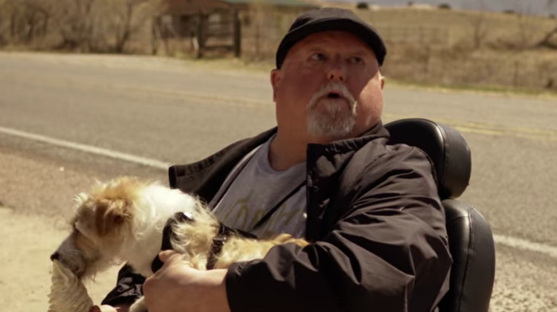 Man in wheelchair and dog licking ice cream