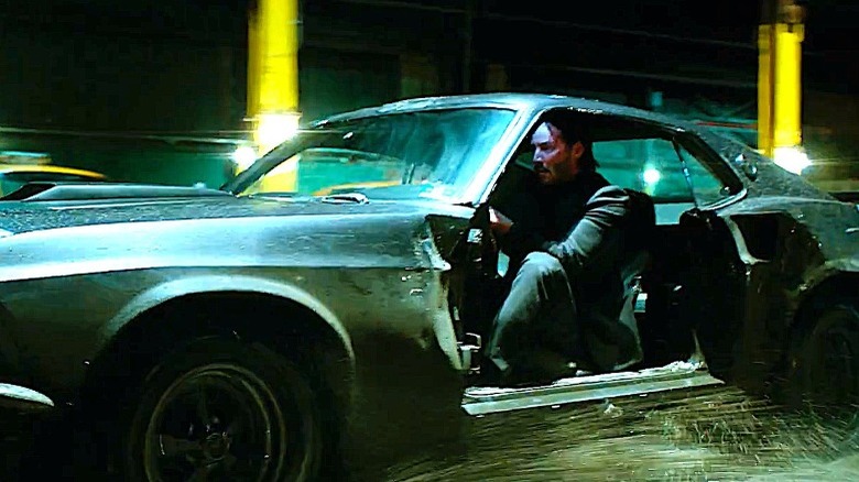 John Wick driving his wrecked Mustang