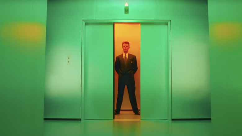 David Bowie stands in an elevator at the end of a green hallway