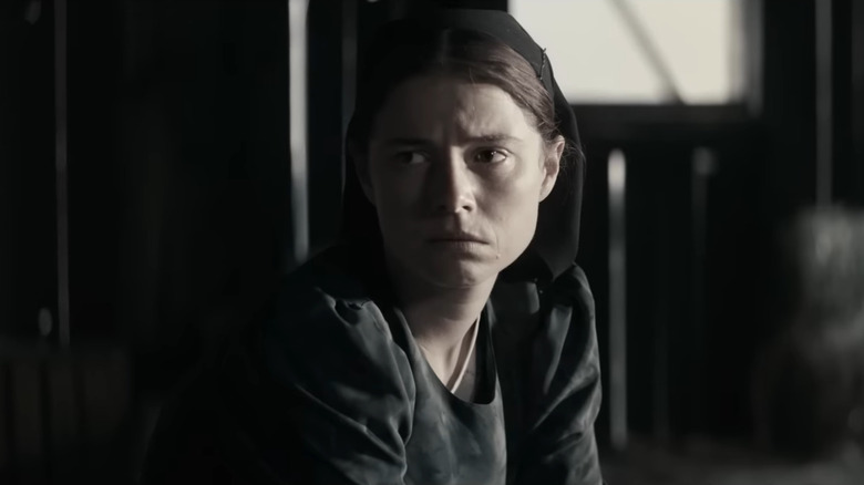 Jessie Buckley looking solemn in barn