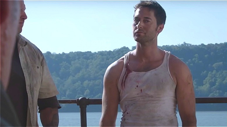 Tom wearing a white tank top looking dirty and bloodied