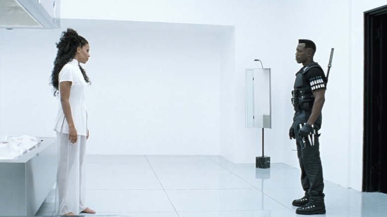 A man in black and a woman in white stand in a stark white room