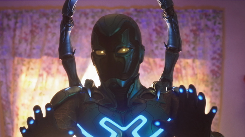 Blue beetle holding up hands