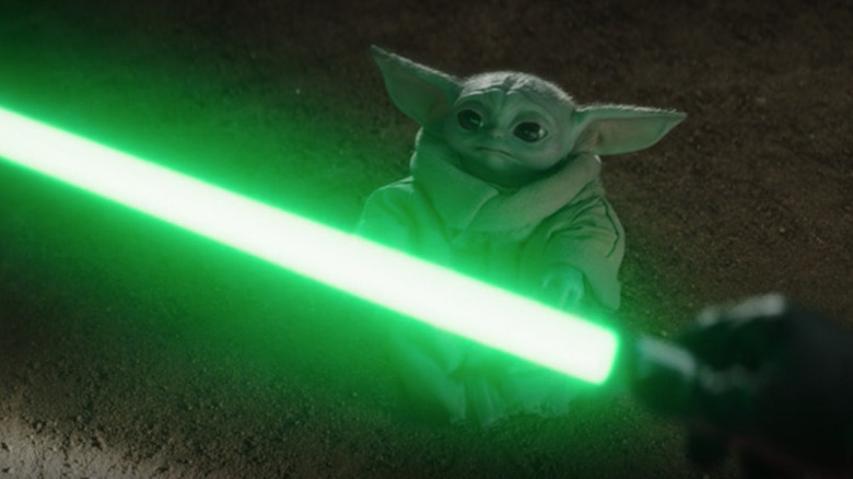 Grogu staring at Yoda's lightsaber