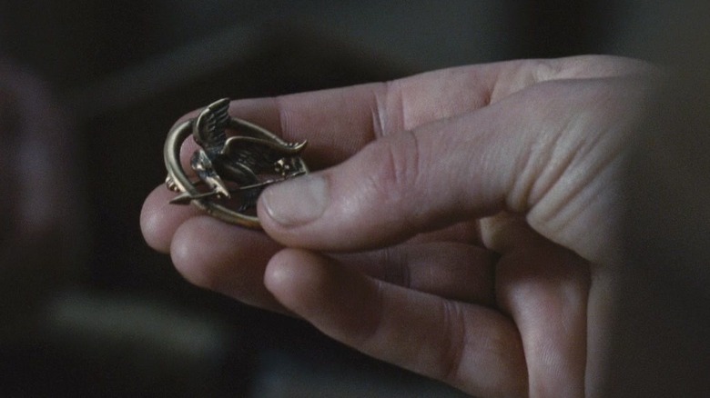 Katniss' hand holding the mockingjay pin