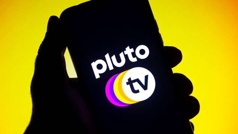 Pluto TV logo on iPhone in front of yellow background