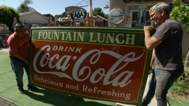 Juan Robbie Wolfe carrying giant Coca-Cola sign