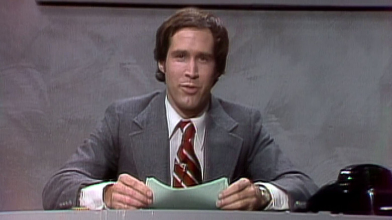 Chevy Chase sits at desk reading