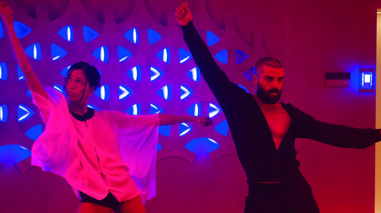 Oscar Isaac and Sonoya Mizuno dancing in neon red and blue light