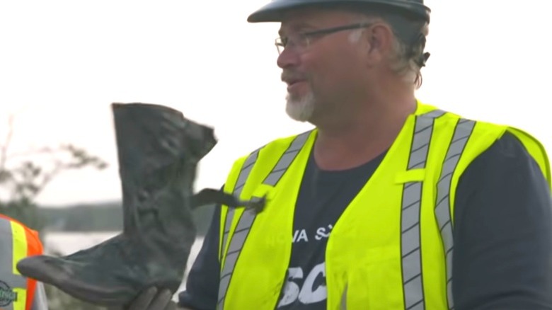 An excavator holding a rubber boot on "The Curse of Oak Island"