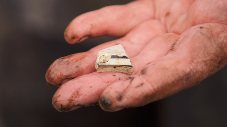 hand holds pottery shard