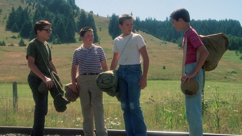 Vern, Gordie, Chris, and Teddy walking on train tracks