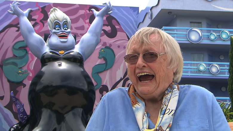 Pat Carroll laughing in front of an Ursula statue