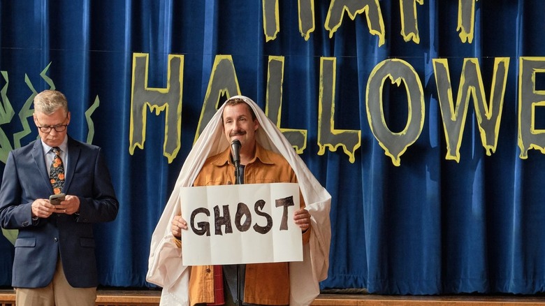 Adam Sandler holding a card that reads "ghost"